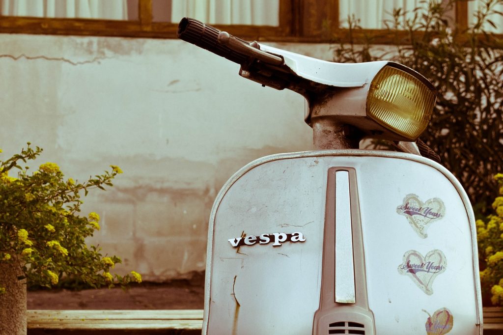 Vespa klasik vintage berwarna terang terparkir di pinggir jalan